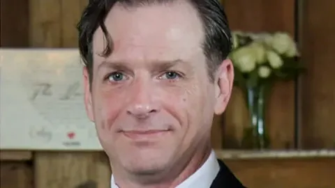 Architectural drafter Coby Godfrey standing in front of a mantel