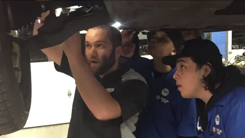 Auto mechanic Jake Sorensen shows technicians how to fix something on a car