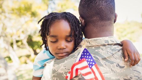 Young girl hugs her dad with an American flag in her hand