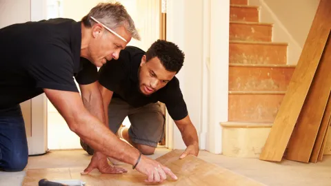 Two men work on flooring, example of on the job training