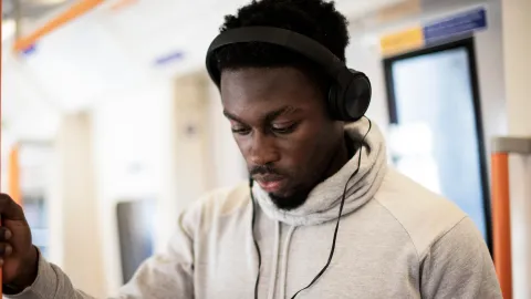 Man on train listens to construction podcast on headphones
