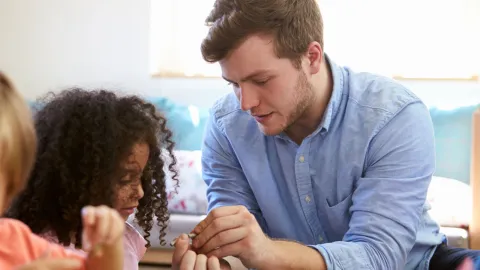 Young male preschool teacher works with a child to solve a puzzle. Example of associate degree jobs that may surprise you.