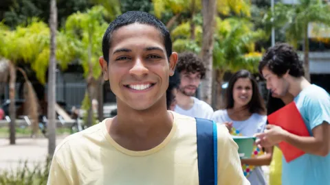 Happy young black man with friends behind him. Benefit of trade school scholarships and grants in supporting young people