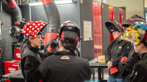 A group of women welders at Lincoln Electric discuss a task. 