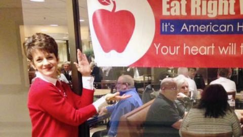 Registered dietician Catherine Shaw stands in front of a sign that reads Eat Right, West Virginia