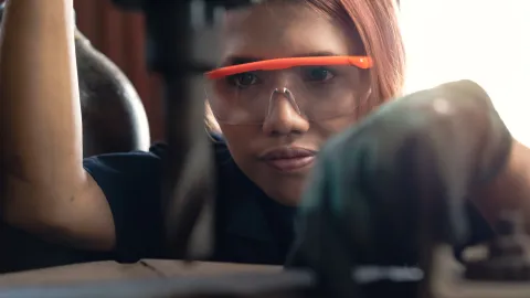 female student operating factory drill machinery