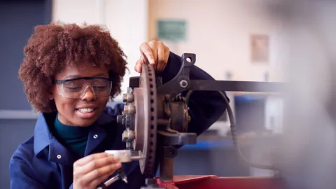 Young black teen works with a wheel in a vocational tech center. Example of micro credentials and how they open up new pathways