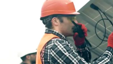 A graduate of Palm Beach State College works with a solar panel.