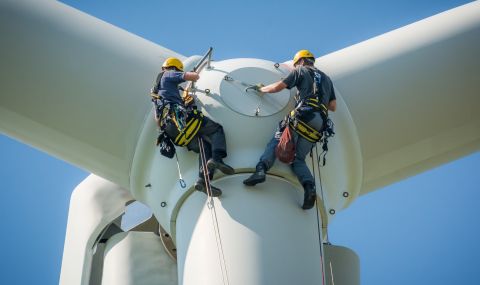 Wind turbine technicians inspect a turbine at a wind farm