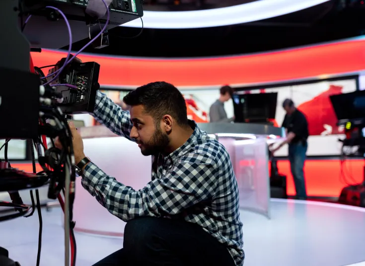 An AV technician sets up audio and video equipment for a broadcast