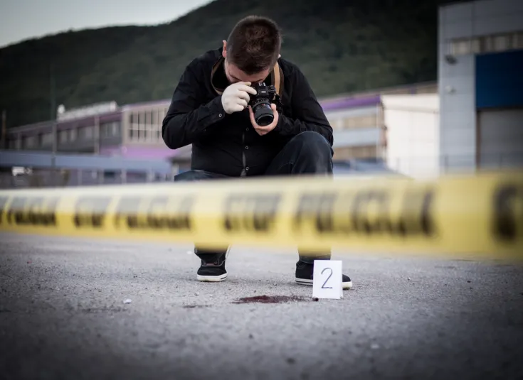 A criminal investigator takes photos at a crime scene