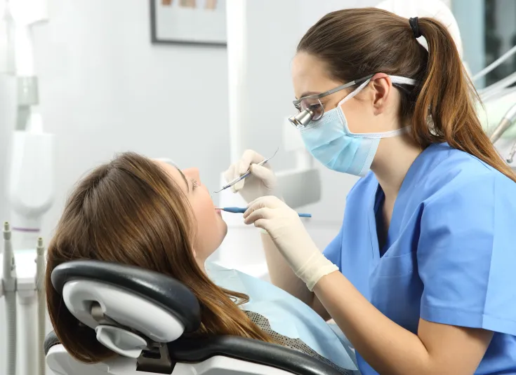 A dental hygienist cleans a patient’s teeth