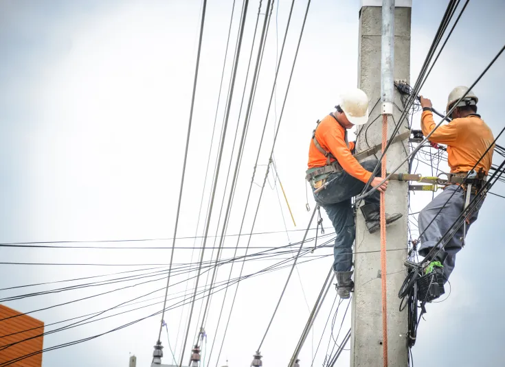 Electrical linemen work on a power line pole