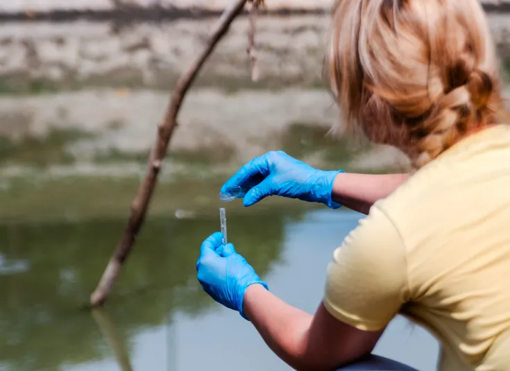 An environmental field technician collects a water sample