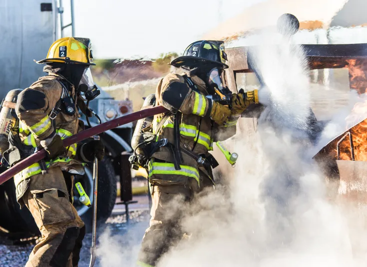 Firefighters work together in a training exercise to put out a fire