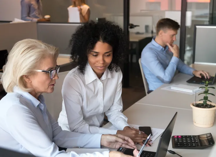 An IT support specialist helps an employee solve computer issues.