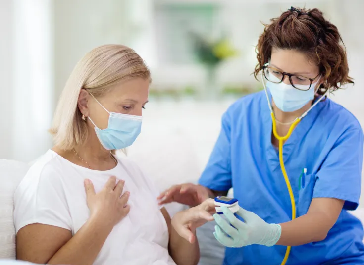 A licensed practical nurse tests a patient’s blood oxygen level with a pulse oximeter