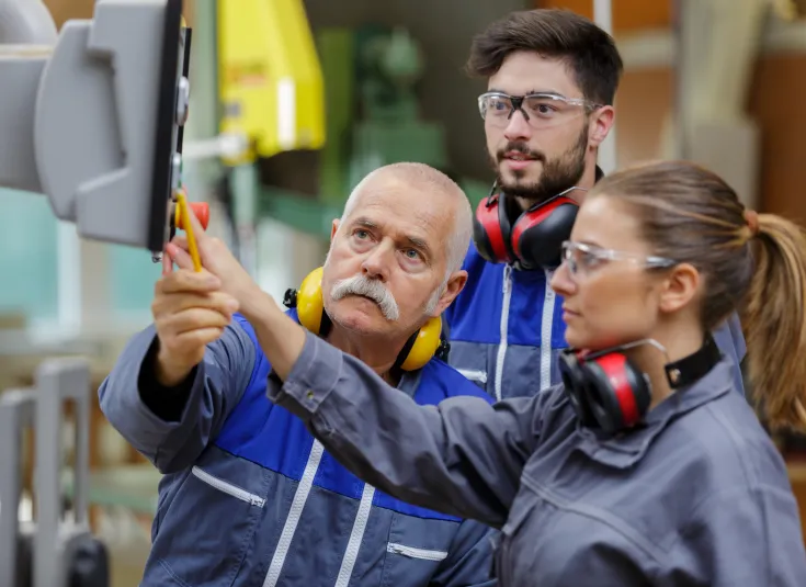 Apprentices learn how to run a computer control panel in a machine shop