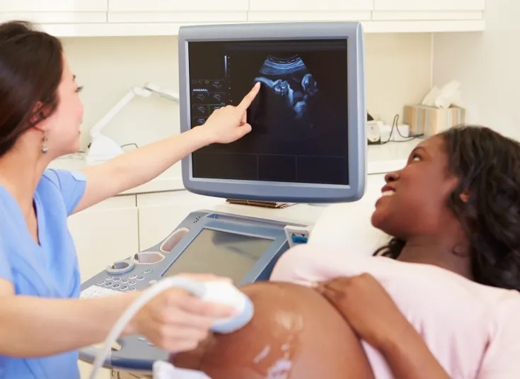 A diagnostic medical sonographer shows a pregnant woman an ultrasound of her baby