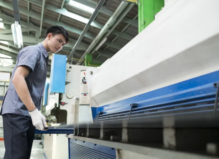 A metal fabricator uses a hydraulic punching machine on a piece of metal
