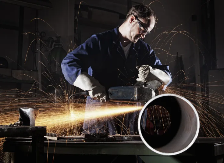A pipefitter cuts a steel pipe before installation