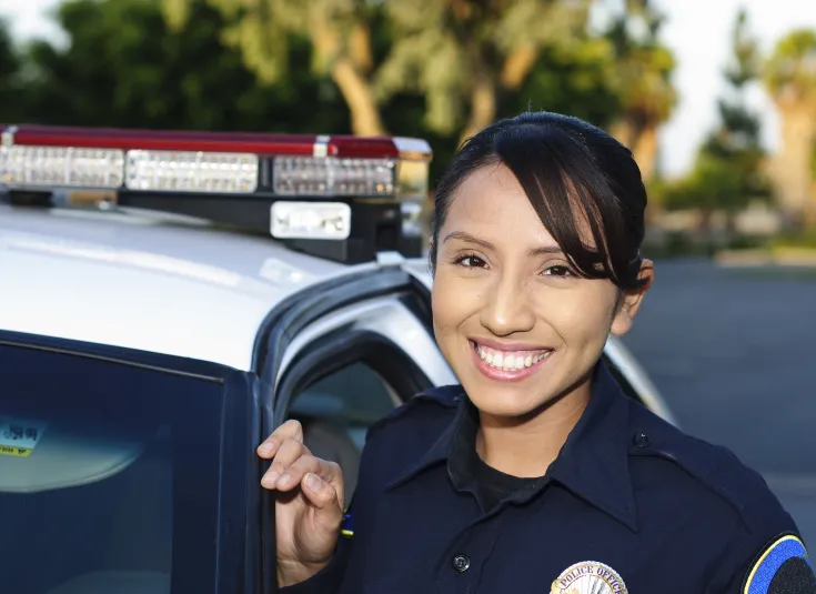 Female police officer stands by her patrol car