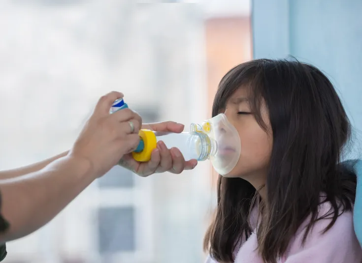 Respiratory therapist uses an inhaler to help a young girl experiencing breathing problems