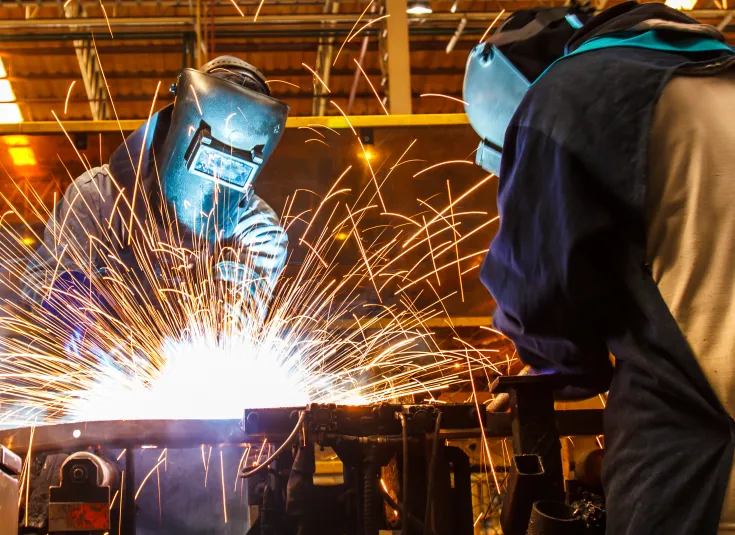 Two welders cut metal in an automotive factory