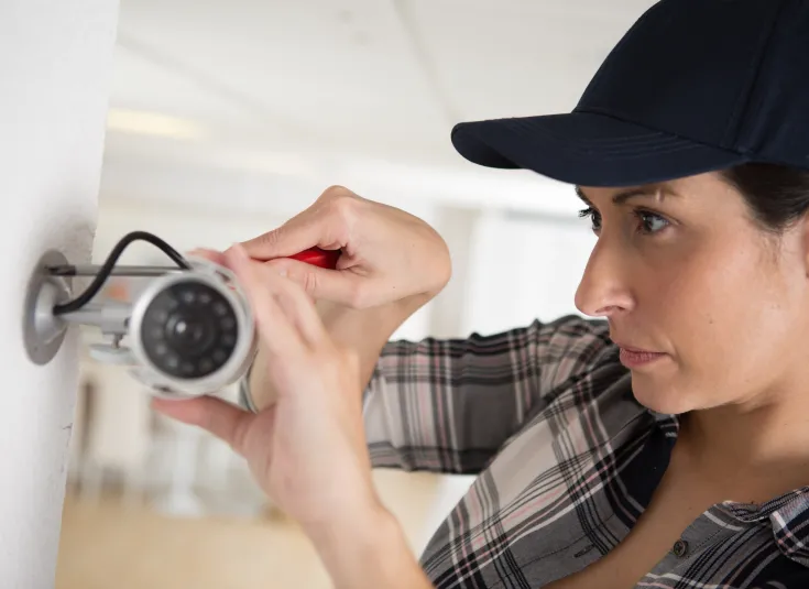 A security alarm installer adjusts a surveillance camera