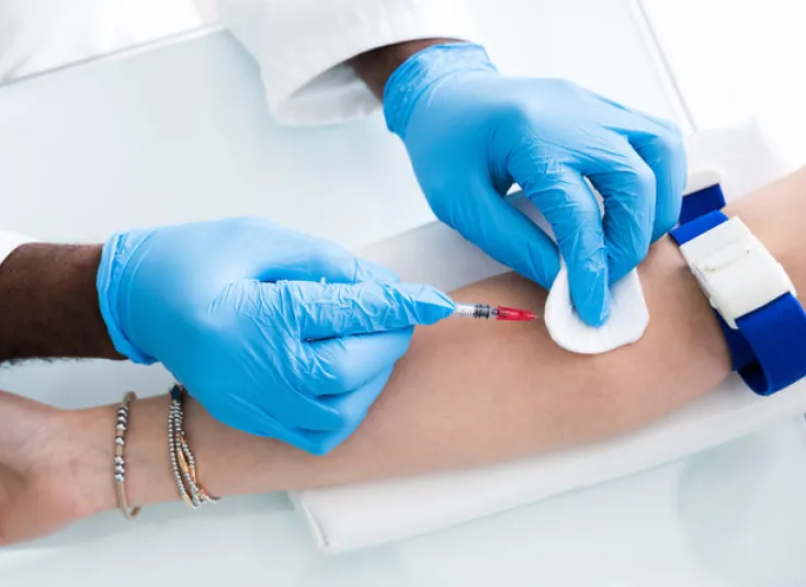 Phlebotomist inserts a needle to take a blood sample