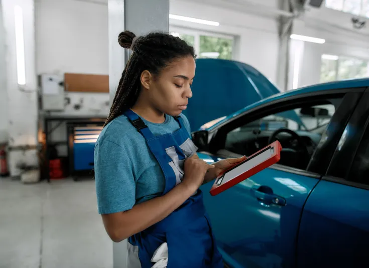 Female auto mechanic uses an advanced computer with diagnostic software to inspect a vehicle