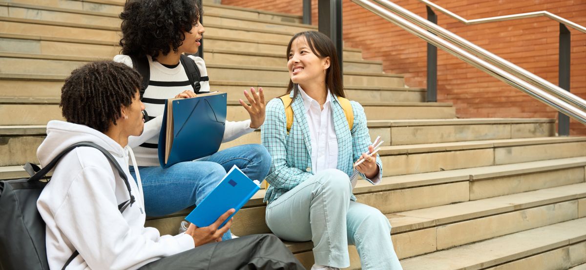 Students sitting on the steps of a college building