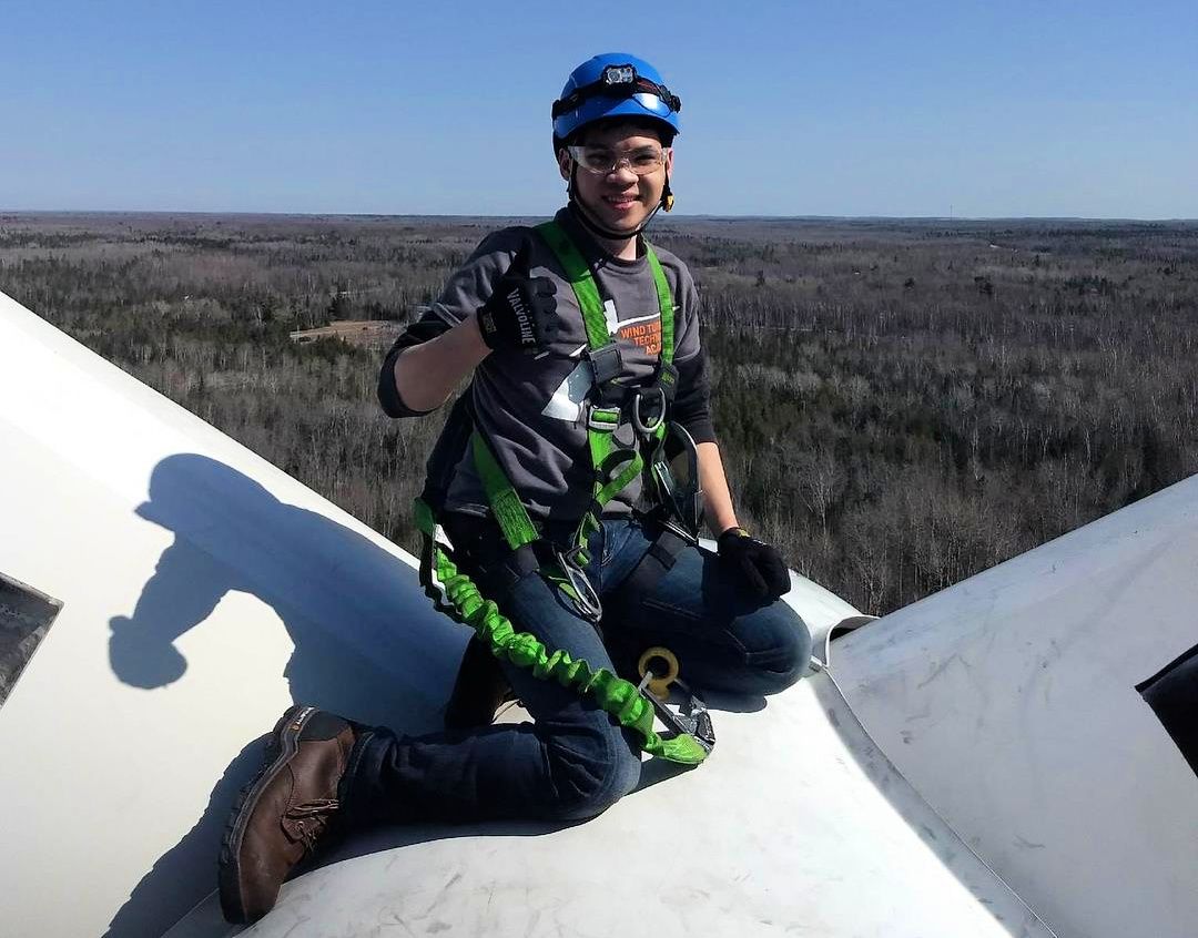 Charlie Tran, wind turbine technician, gives the thumbs-up on top of a wind turbine