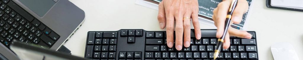 Close-up photo of hands typing on a computer keyboard.