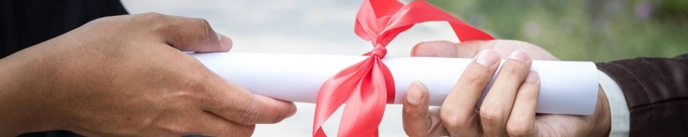 Two hands holding a rolled piece of white paper wrapped in a red ribbon.