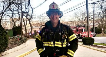 Jeffrey Kaplan, firefighter ambassador, stands in front of a firetruck in his gear
