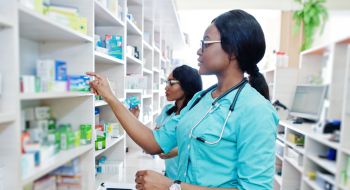 two Black female pharmacy technicians work in a pharmacy, example of pharmacy technician training