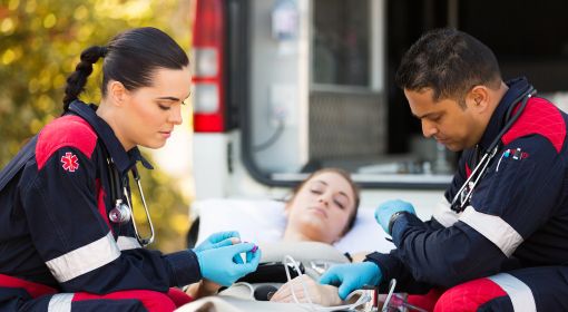 Two paramedics check a patient's vitals and transport her to an ambulance during an emergency