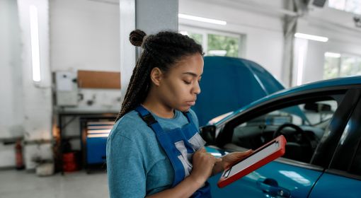 Female auto mechanic uses an advanced computer with diagnostic software to inspect a vehicle