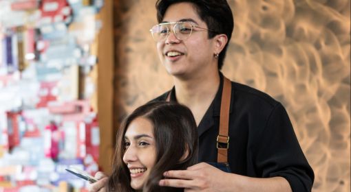 Young Asian hairdresser styles a young woman's hair at a salon