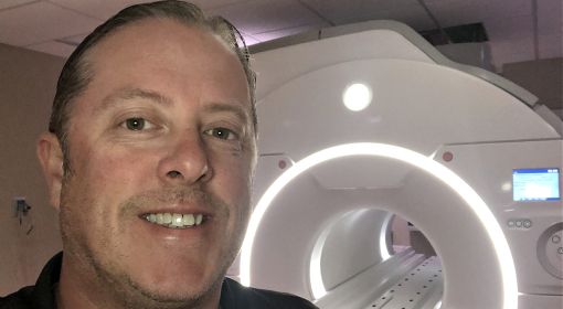 Joseph Seibert, MRI tech ambassador, stands in front of an MRI machine