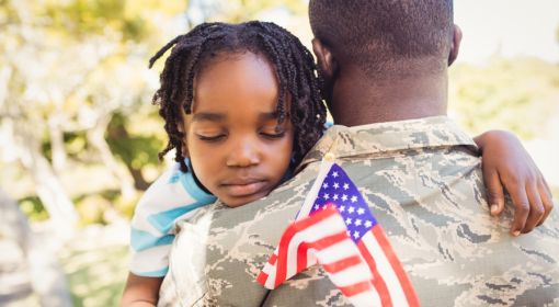 Young girl hugs her dad with an American flag in her hand