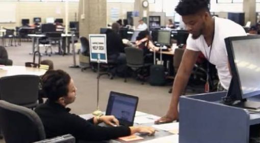 Students at Cuyahoga Community College work on computers and speak with eachother.