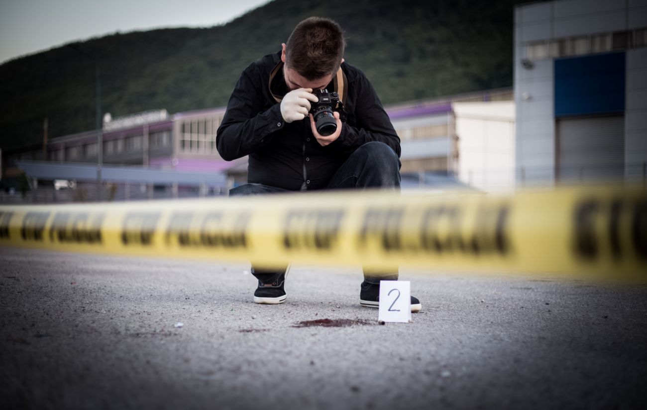 A criminal investigator takes photos at a crime scene