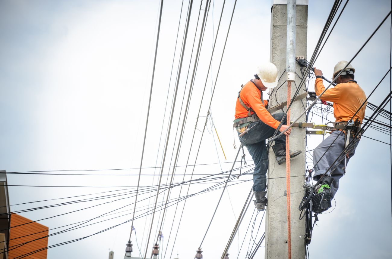 Electrical linemen work on a power line pole