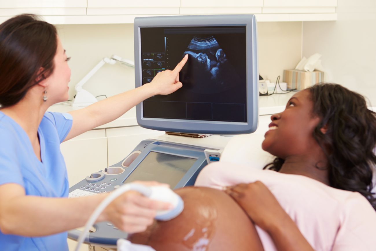 A diagnostic medical sonographer shows a pregnant woman an ultrasound of her baby