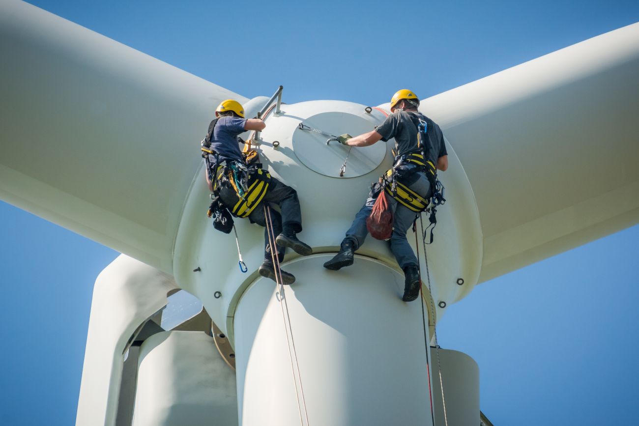Wind turbine technicians inspect a turbine at a wind farm