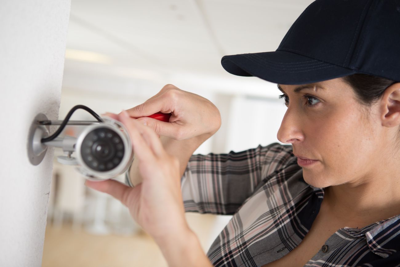 A security alarm installer adjusts a surveillance camera