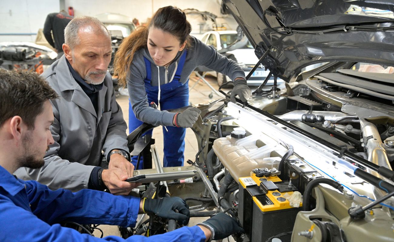 Instructor and students work on a car engine