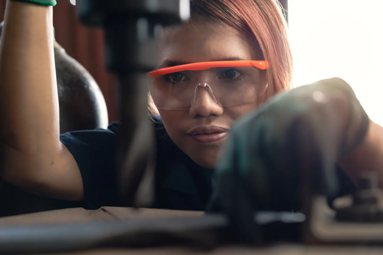female student operating factory drill machinery